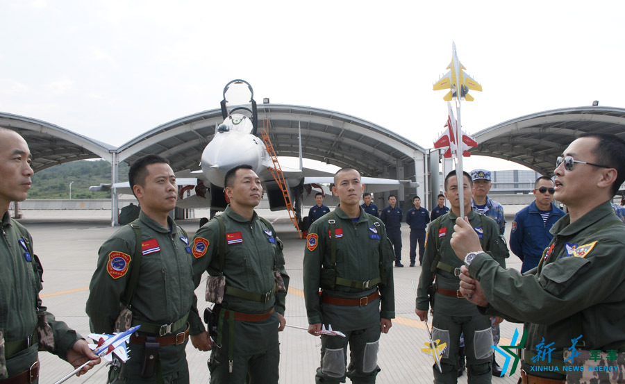 ↑艦載航空兵某部司令員戴明盟向飛行員演示空中飛行注意事項。