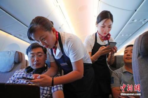 資料圖：乘務(wù)員們?cè)诳团搩?nèi)為旅客調(diào)試機(jī)上上網(wǎng)功能。<a target='_blank' ><p  align=